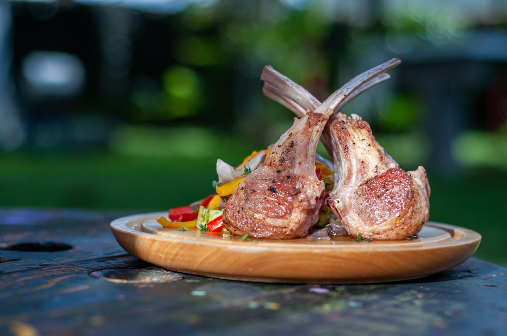 a wooden plate topped with meat and vegetables