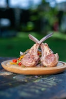 a wooden plate topped with meat on top of a wooden table