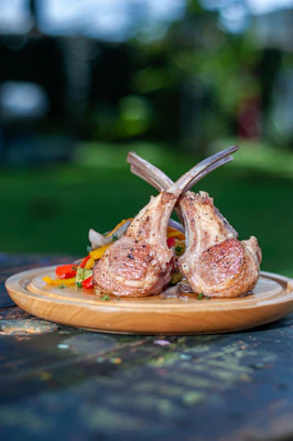 Tender lamb chops displayed on a rustic platter with garlic and herbs, ready for cooking.