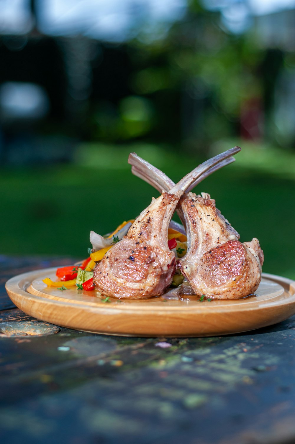 a wooden plate topped with meat on top of a wooden table