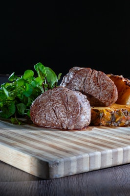 a wooden cutting board topped with meat and vegetables