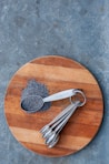 a wooden cutting board topped with metal spoons