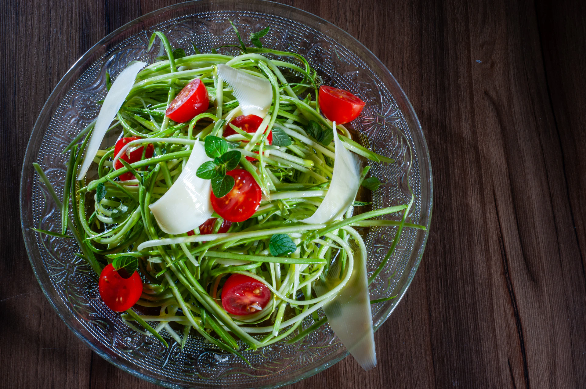 a glass bowl filled with a salad on top of a wooden table