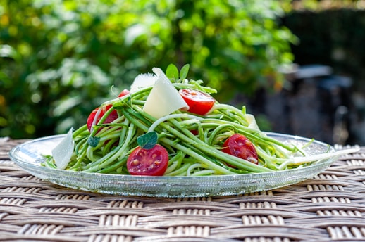 a plate of pasta with tomatoes and green beans