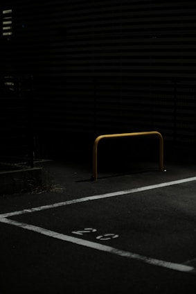 A sturdy metal parking barrier installed in an outdoor parking lot.