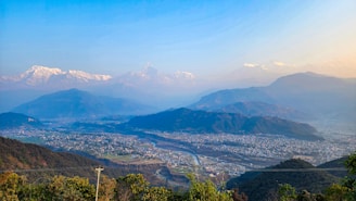 A panoramic view of the Himalayan mountains with a futuristic data center nestled among the peaks, glowing softly at dusk.