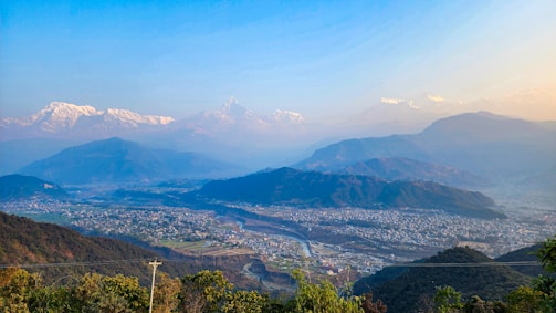 A panoramic view of the Himalayan mountains with a futuristic data center nestled among the peaks, glowing softly at dusk.