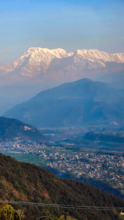 Snow-capped peaks of the Himalayas framing a peaceful mountain village in Manali.