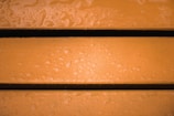 Three wet wooden planks with an orange hue and visible water droplets scattered across the surface.
