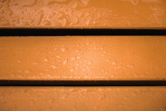 Three wet wooden planks with an orange hue and visible water droplets scattered across the surface.