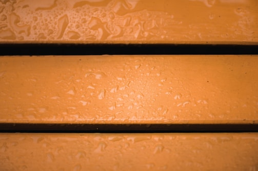 Three wet wooden planks with an orange hue and visible water droplets scattered across the surface.