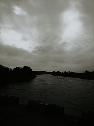 Serene river flowing beside rustic cabins under cloudy skies.
