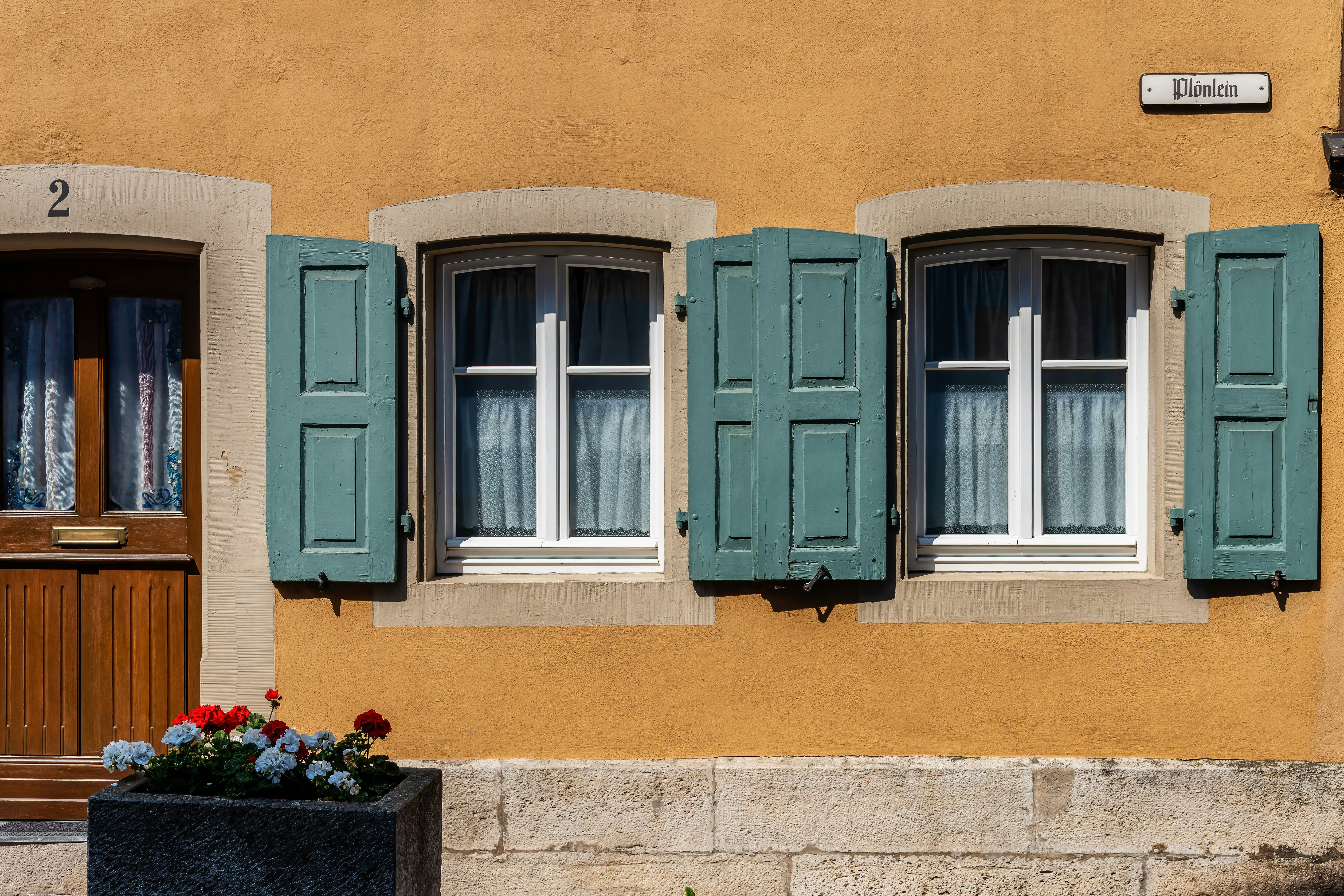 a yellow building with blue shutters and a flower box in front of it