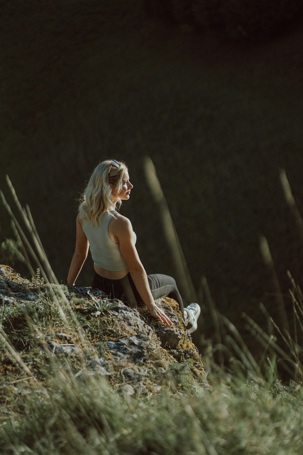 a woman sitting on top of a grass covered hillside