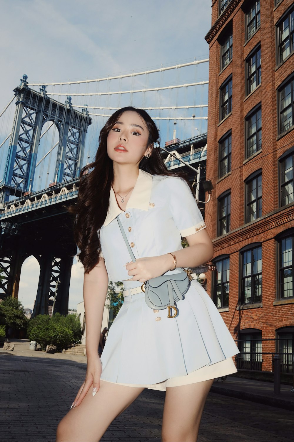 a woman in a short white dress standing in front of a bridge