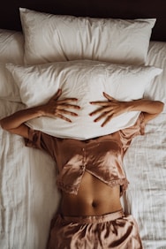 a woman laying in bed with her hands on a pillow