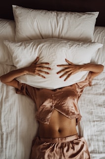 a woman laying in bed with her hands on a pillow
