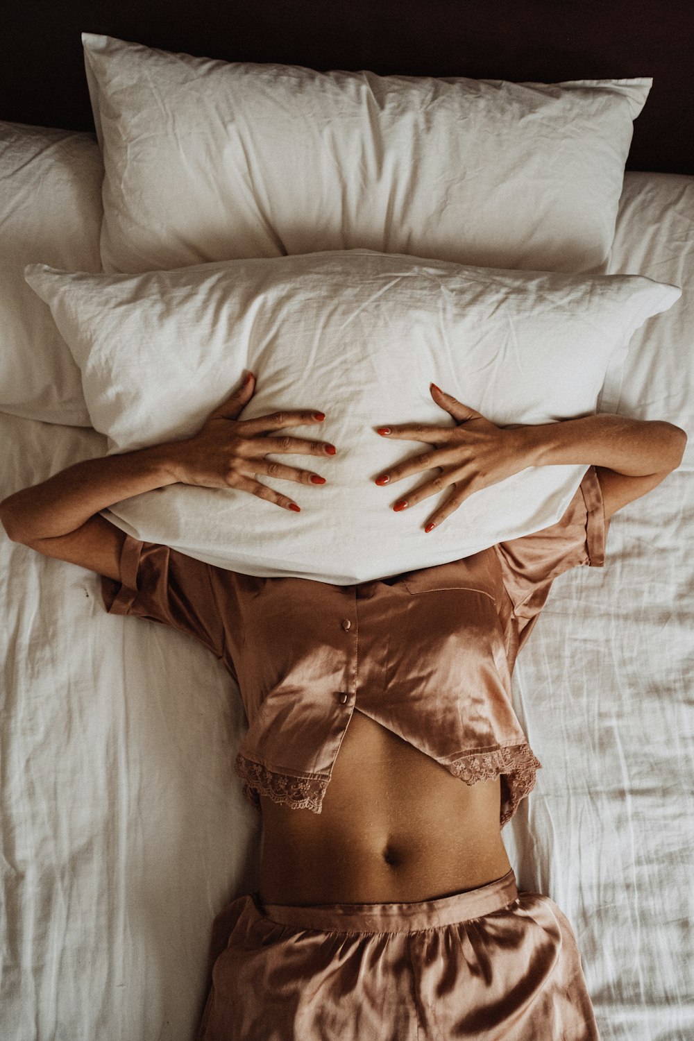 a woman laying in bed with her hands on a pillow