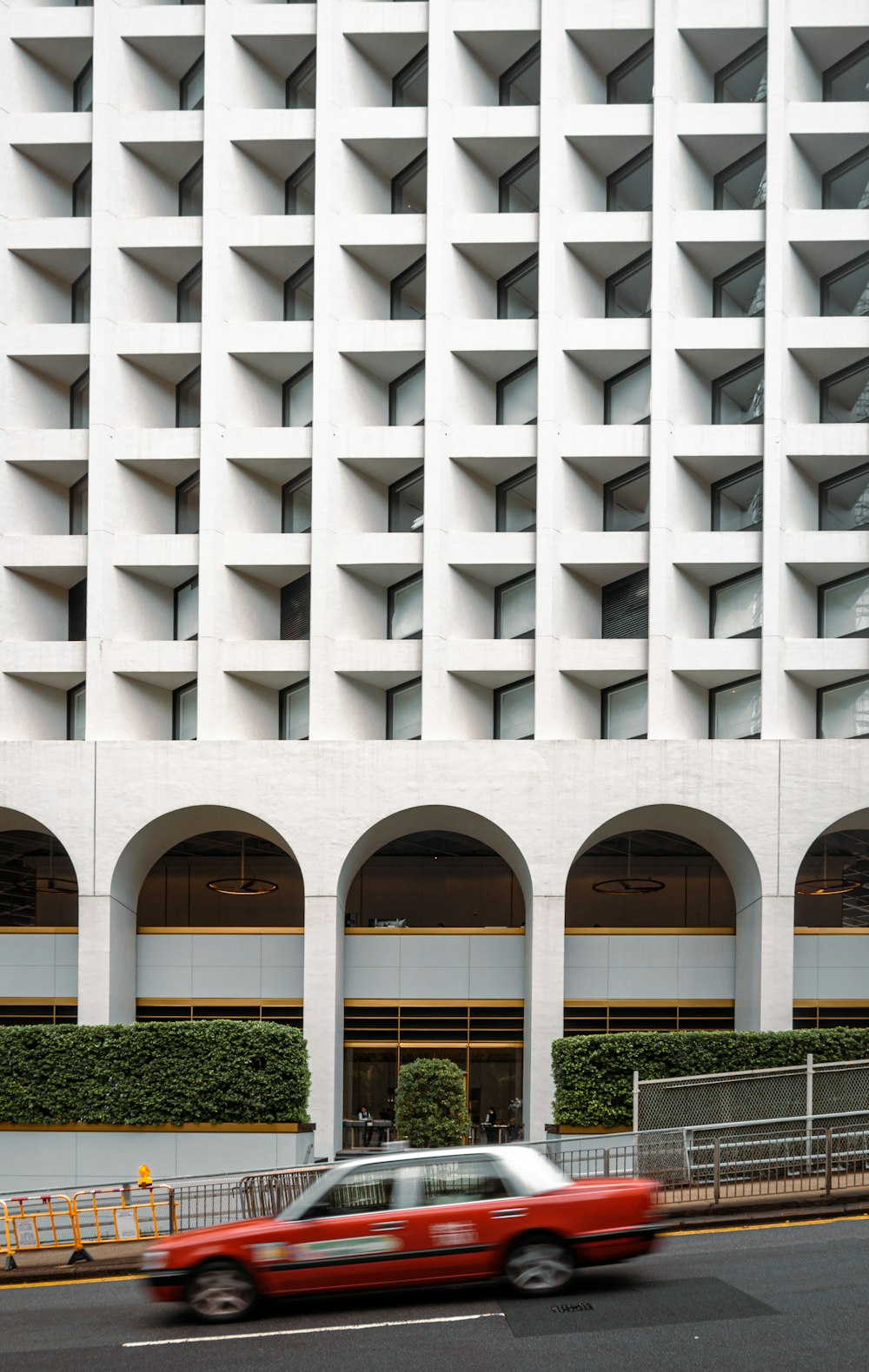 a red car driving past a tall white building