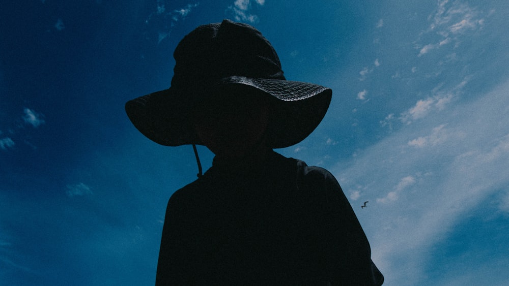 a silhouette of a person wearing a hat