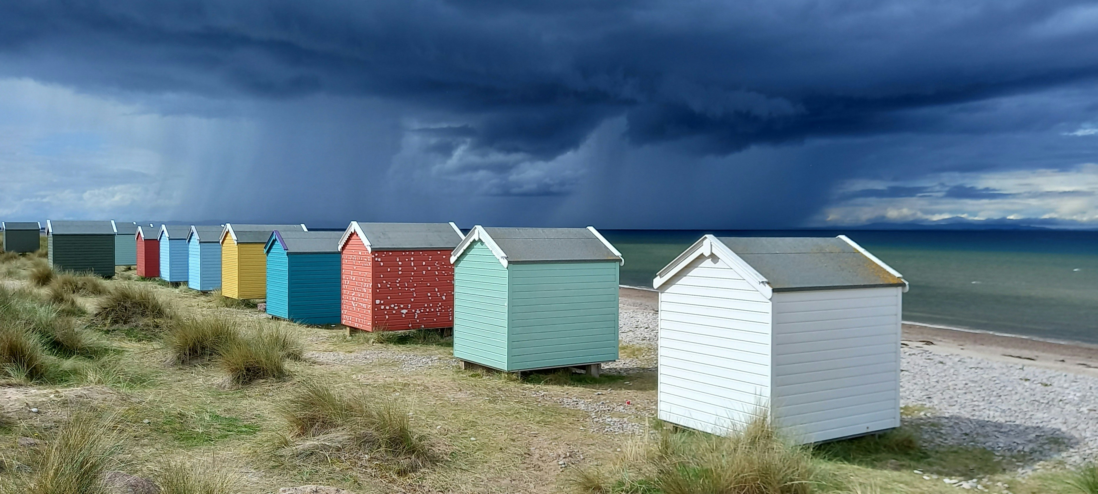 Rain clouds cross the Moray Firth near Findhorn in the north of Scotland. A beautiful beach with colourful beach huts.