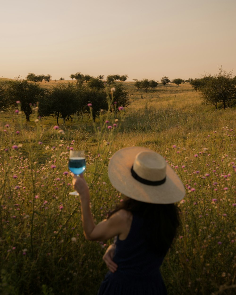 Una donna in un cappello che tiene un bicchiere di vino