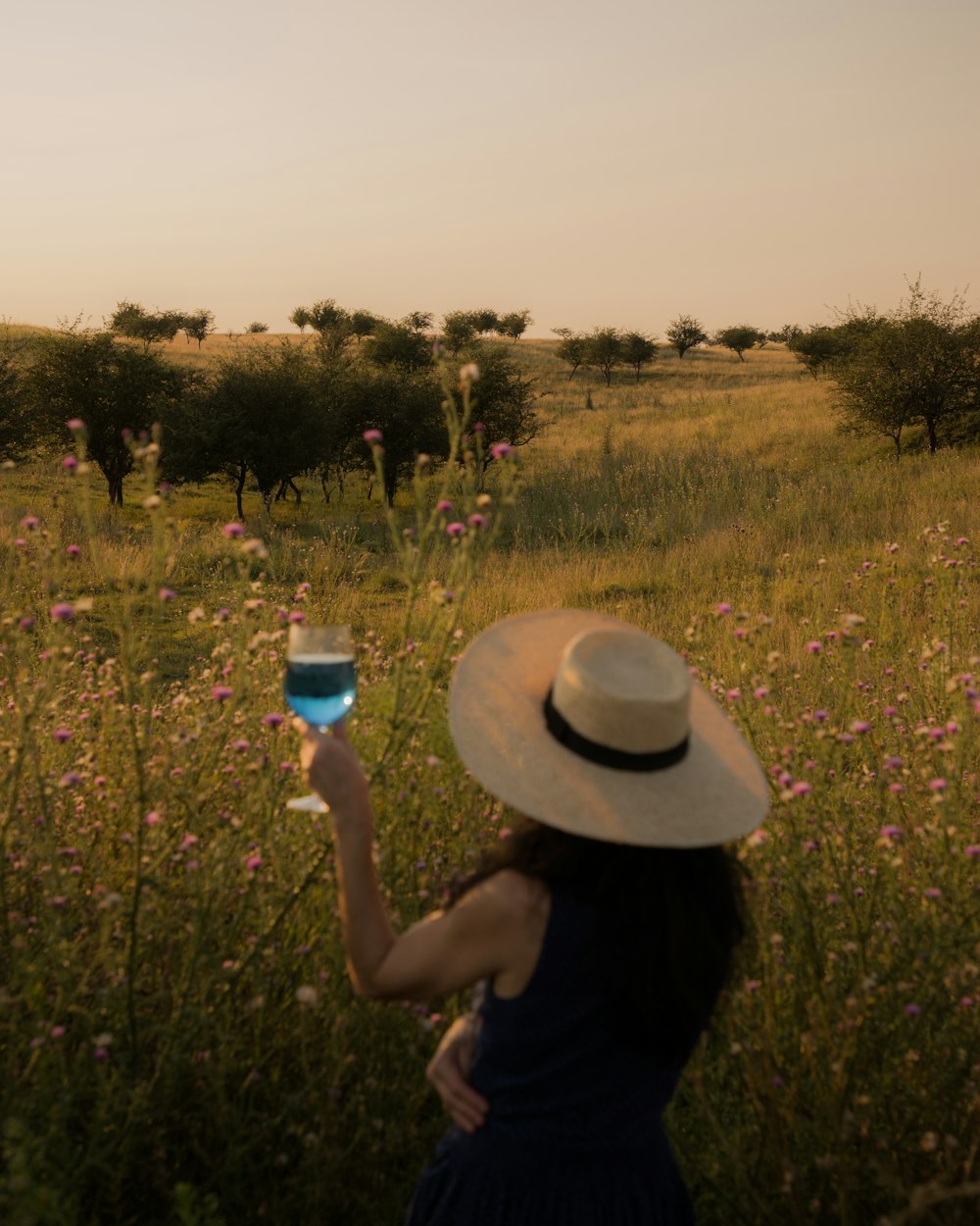 Una mujer con sombrero sosteniendo una copa de vino