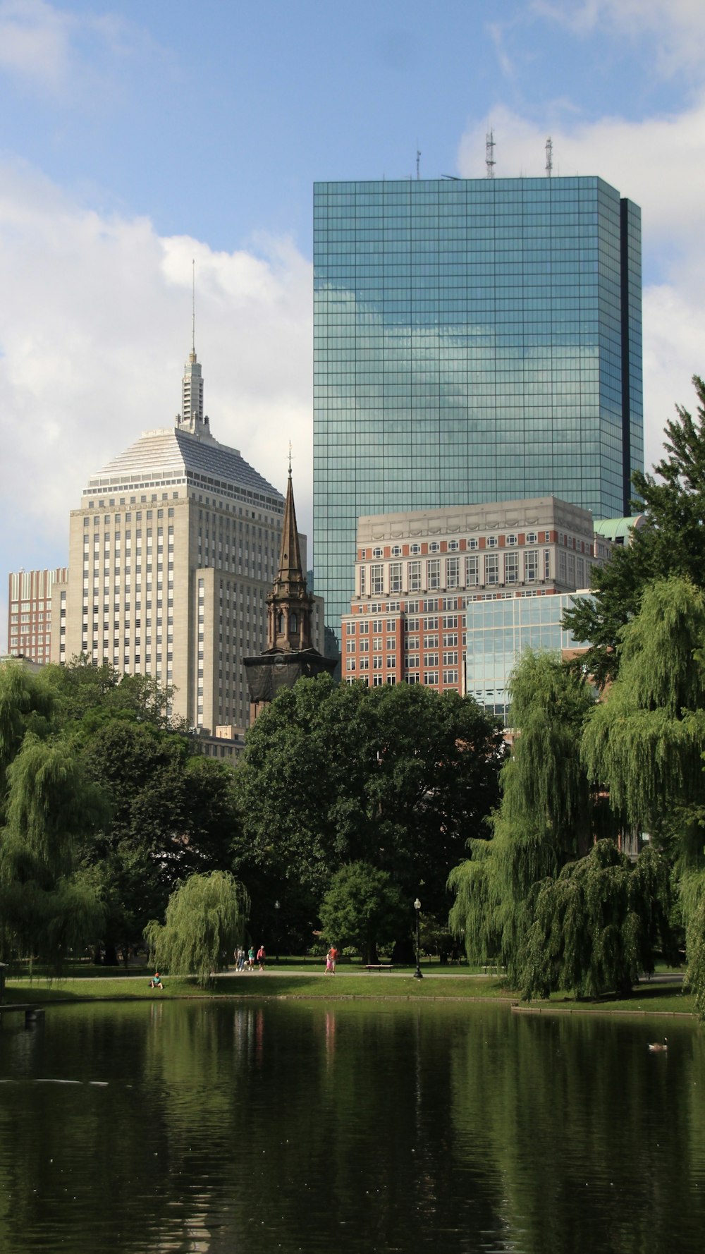 a lake in a city park with tall buildings in the background