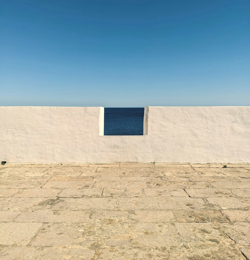 a white wall with a blue ocean in the background