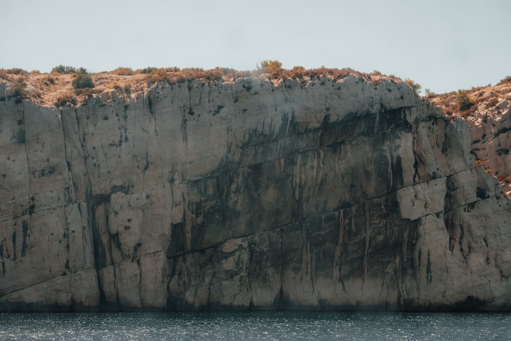 a large rock cliff with a small boat in the water