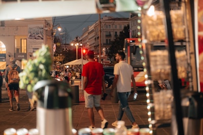 A bustling street corner with people enjoying various food items from mobile stalls at sunset.