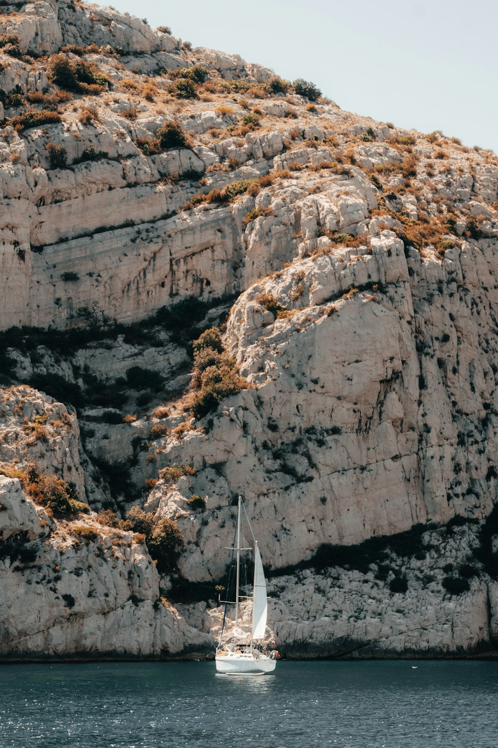 a sailboat in a body of water near a rocky cliff
