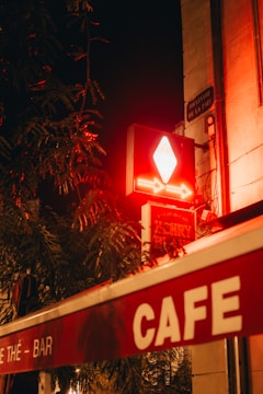 A vibrant neon box sign glowing outside a cozy cafe at night.