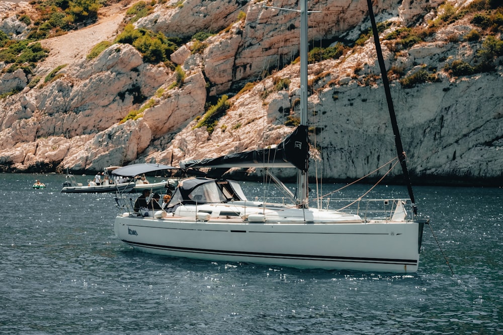 a sailboat in a body of water near a rocky cliff