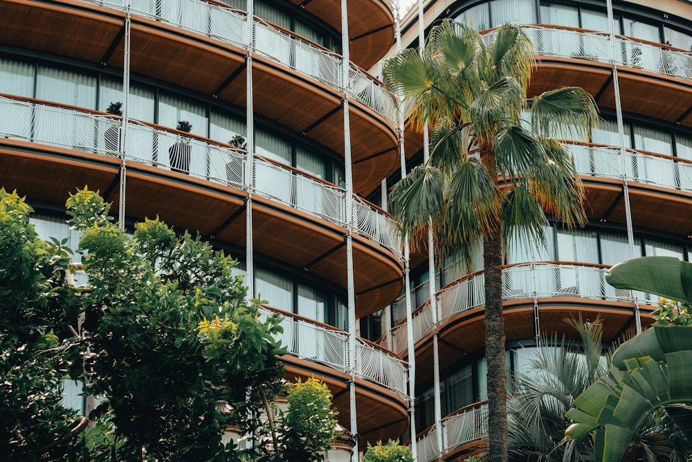 Un edificio alto con balcones y palmeras frente a él