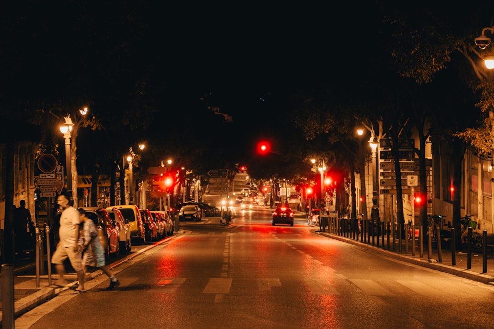 a couple of people walking down a street at night