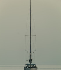 A minimalist composition of a lone sailboat on calm blue waters.