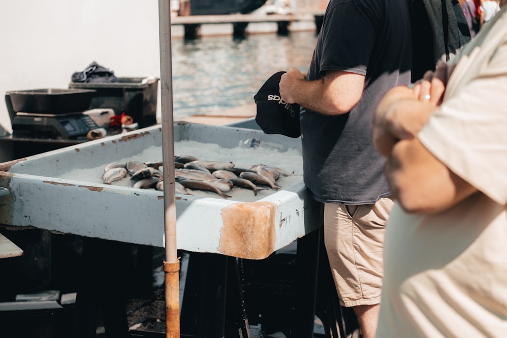 a man standing next to a boat with a bunch of fish on it