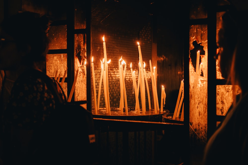 a group of people standing in front of a bunch of lit candles