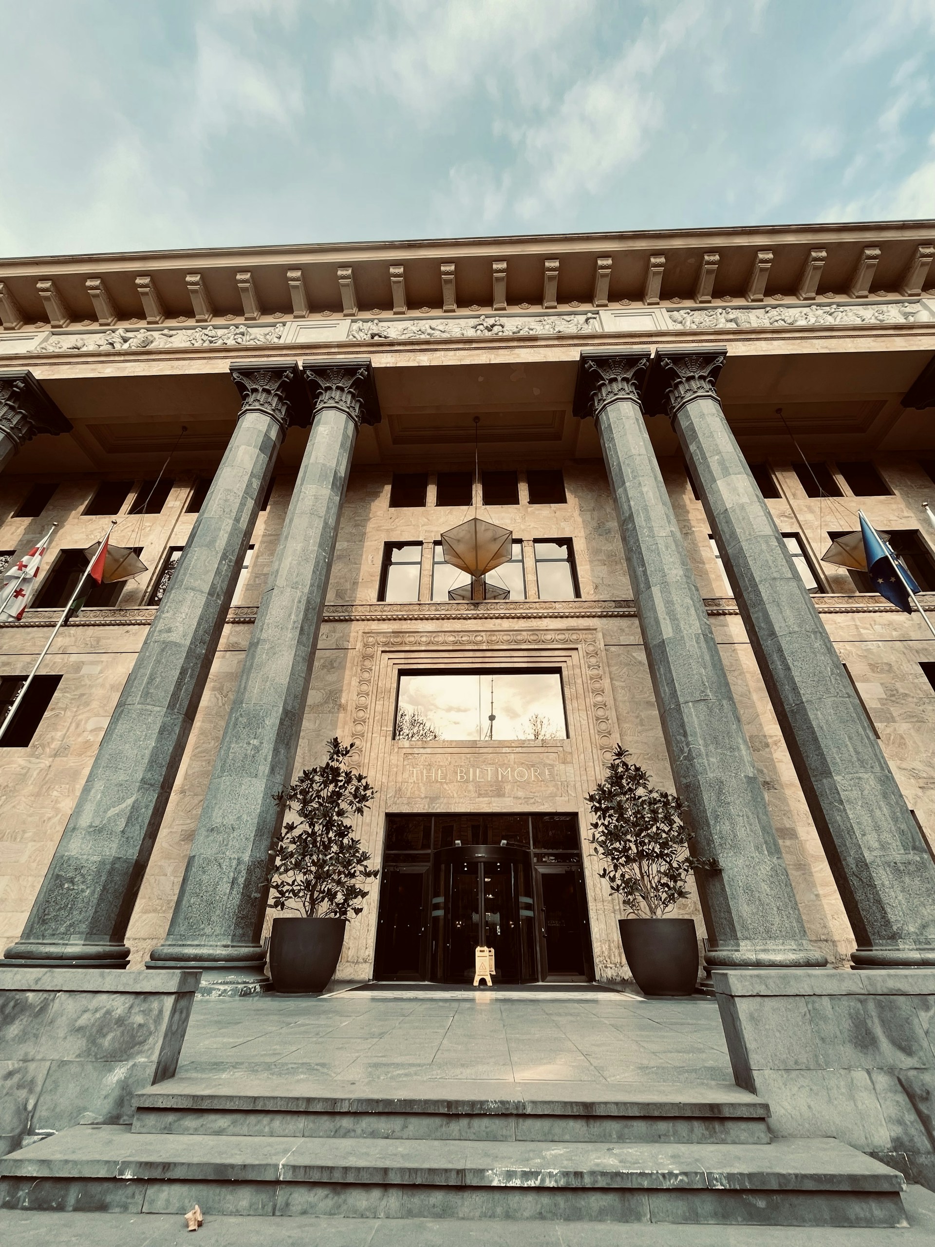 a tall building with columns and a clock on the front of it