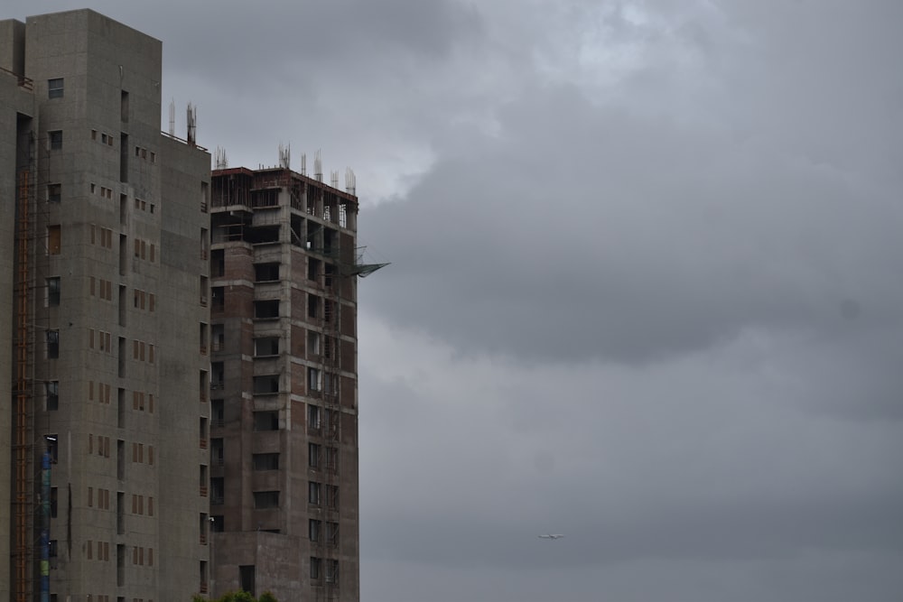 Un edificio muy alto con un avión volando en el cielo