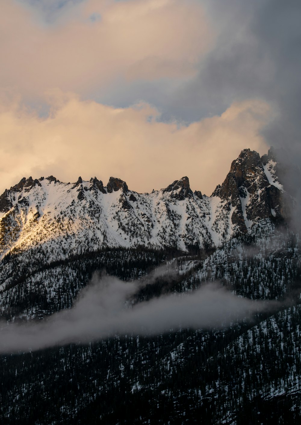 a mountain covered in snow under a cloudy sky