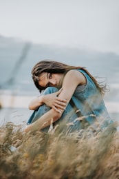 Femme pensive enla&ccedil;ant ses bras, &eacute;voquant la profondeur de traitement &eacute;motionnel propre &agrave; la haute sensibilit&eacute;