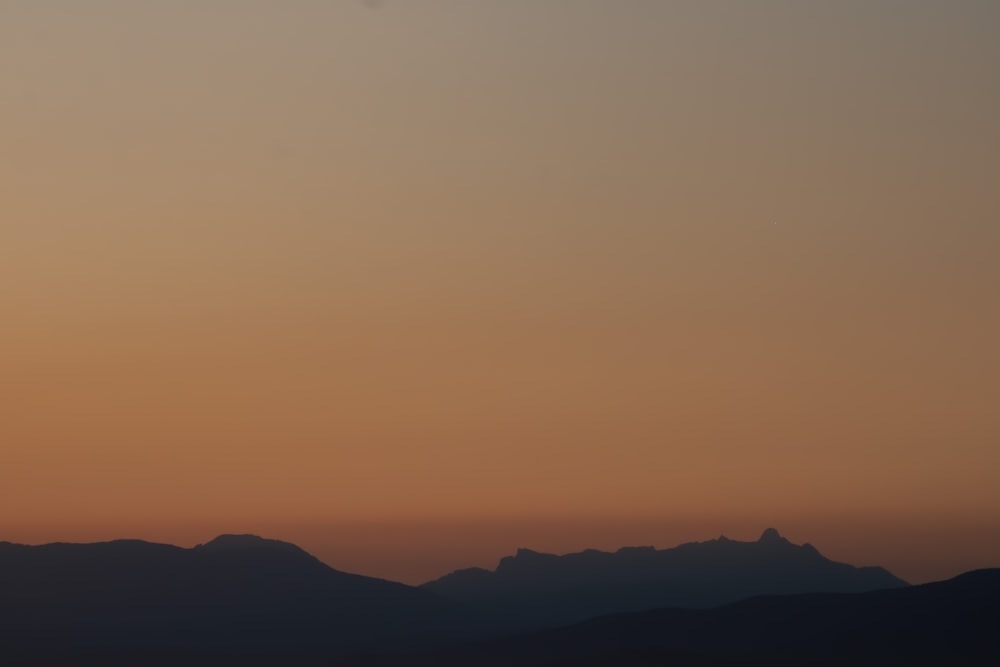 a plane flying over a mountain range at sunset