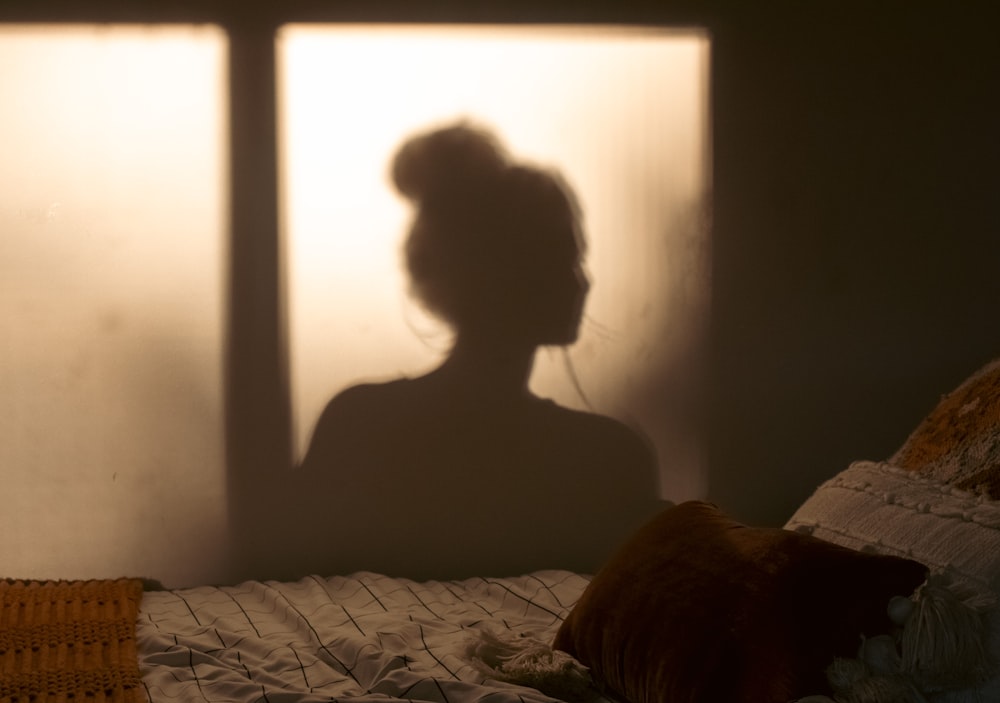 a shadow of a woman sitting on a bed