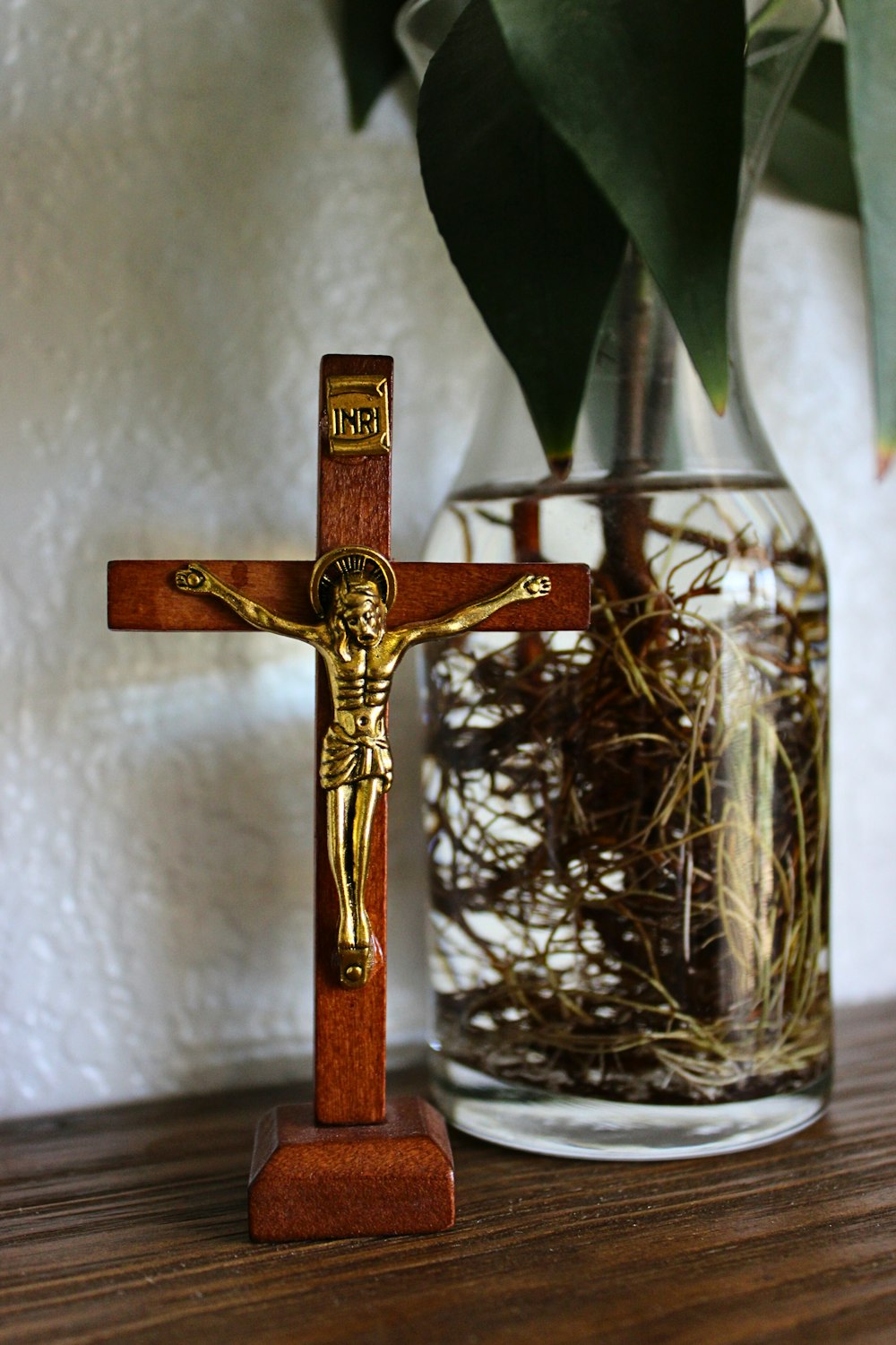 a crucifix on a table next to a vase of flowers