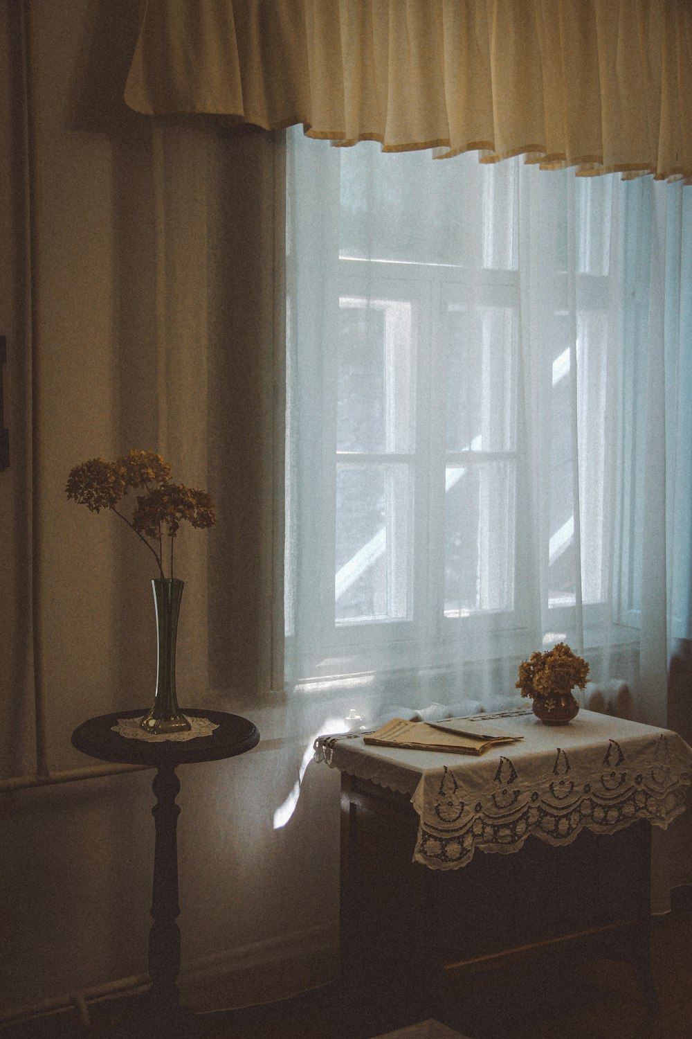 a table with a vase of flowers on it next to a window