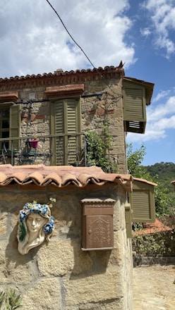 Close-up of the villa’s classic Italian architecture with olive green shutters and beige stone walls.