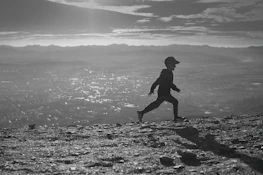 Dynamic shot of a man running at sunset with futuristic city skyline in the background.