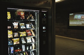 Friendly vending company staff restocking machines with fresh snacks in a college hallway.